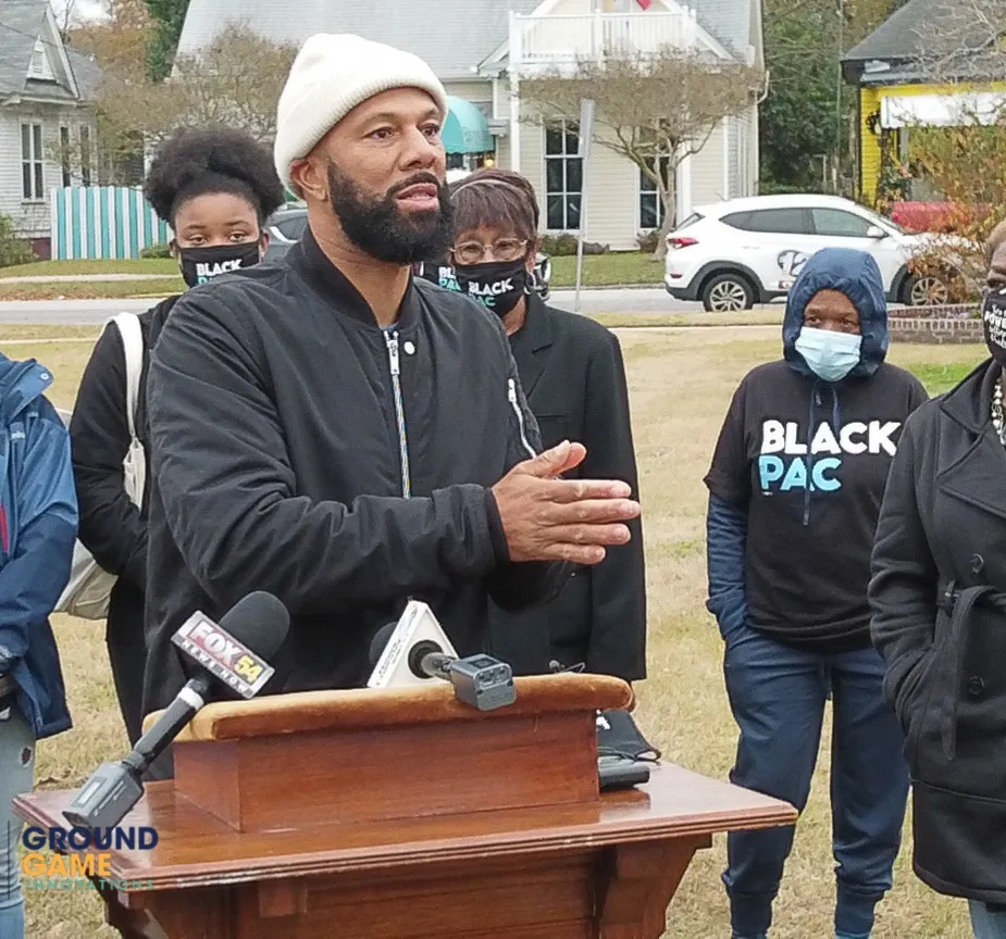 A speaker at a podium with BlackPAC volunteers behind him